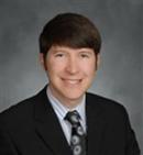 a man in a suit and tie is smiling for the camera .
